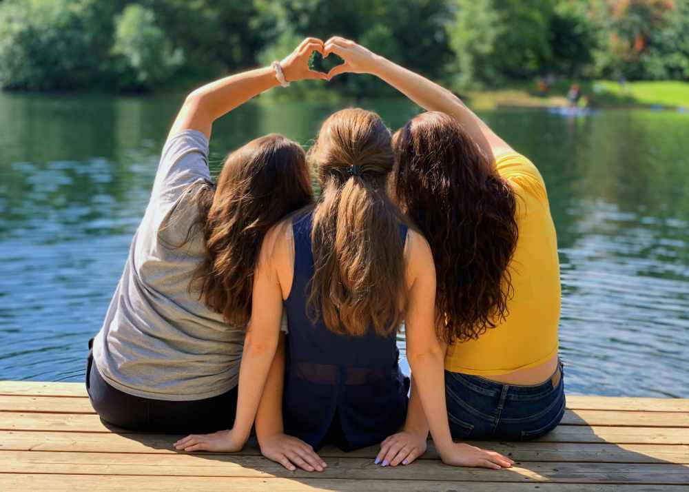 Summer Camp and Head Lice Children Sitting Closely On A Dock in Front of a Lake | Lice Sisters Lice Treatment